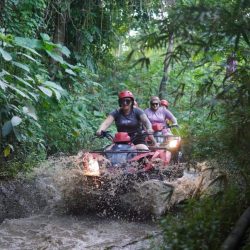 Perahu rafting berisi empat orang melintasi arus sungai yang berbatu di Ubud.
